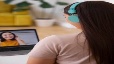 Participante de curso online assistindo a aula em vídeo com fones de ouvido em ambiente doméstico