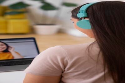 Participante de curso online assistindo a aula em vídeo com fones de ouvido em ambiente doméstico
